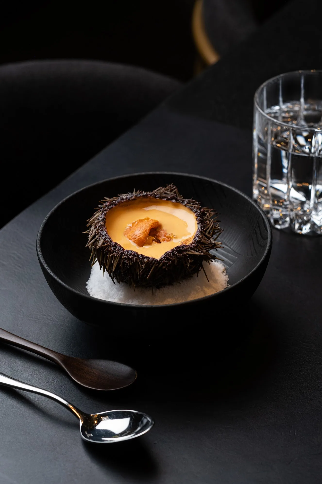 Sea urchin uni dish served in its shell in a black bowl, photo by Alex Slyadnev
