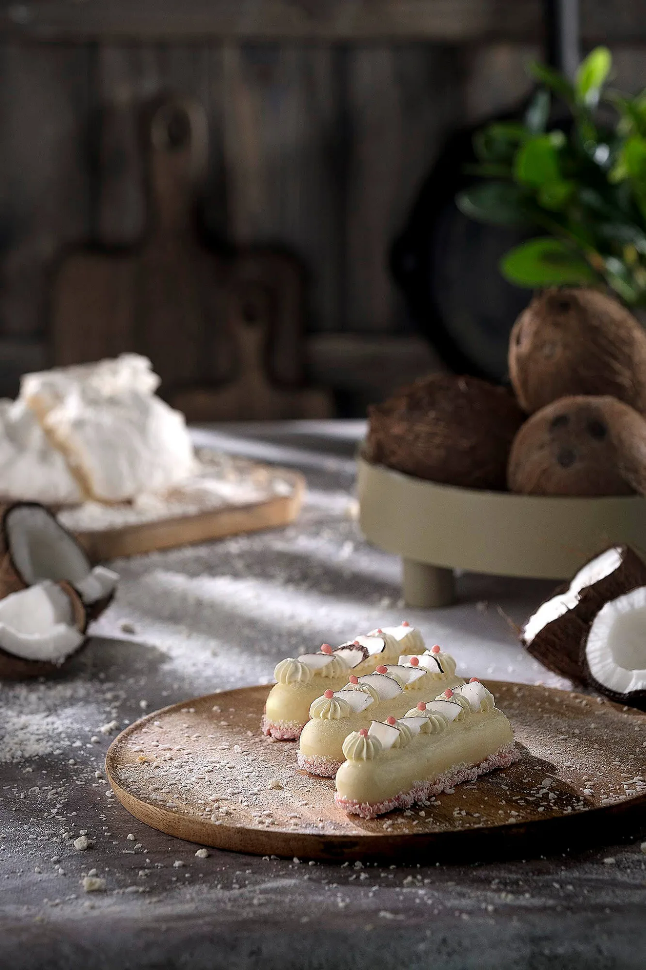 Coconut éclairs on a wooden plate with fresh coconuts, photo by Alex Slyadnev