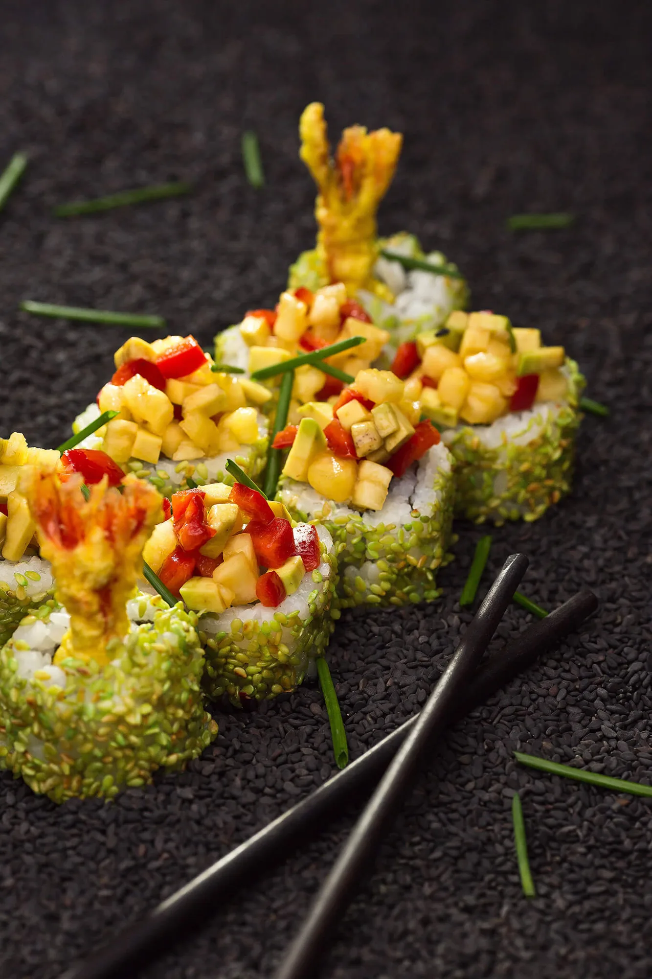 Shrimp tempura sushi rolls topped with mango salsa and chopsticks, photo by Alex Slyadnev