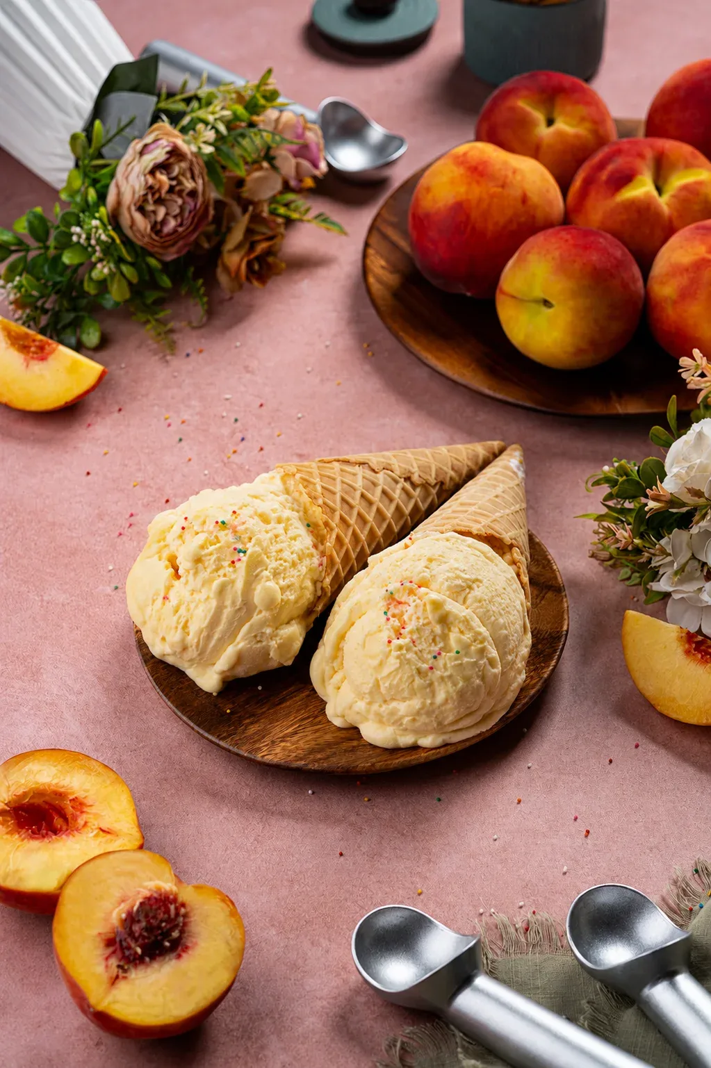 Peach ice cream in waffle cones with fresh peaches on pink table, photo by Alex Slyadnev